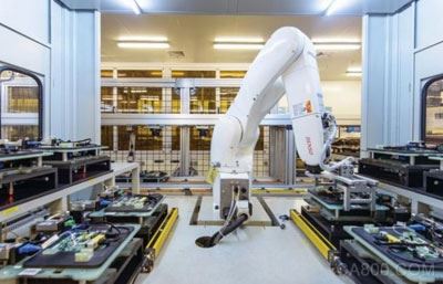 一个机器人臂正在移动电路板进行各种测试。之前这项工作都是由工人手动完成。图片来源MIT TECH REVIEW。